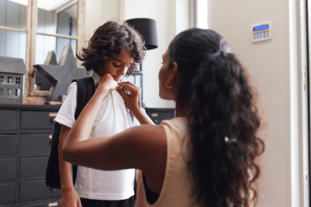 Mãe ajudando filho a se preparar para a escola. 