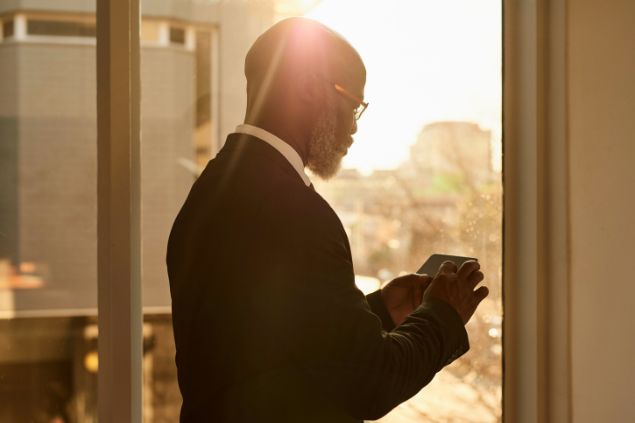 Imagem de um senhor negro mexendo no celular vendo novas oportunidades de trabalho que estão por chegar.