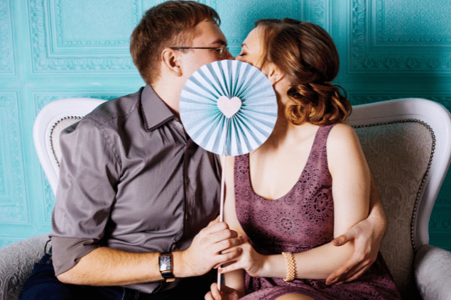 Casal apaixonado se beijando por trás de decoração. 
